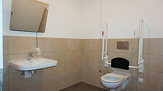 Barierefreies WC Gewerbeeinheit bestehend aus: WC Keramik Vigour Derby Care, WT Keramik Vigour Derby Style, HEWI Kippspiegel, HEWI Stützgriffe, Grohe Eurosmart Einhand Armatur