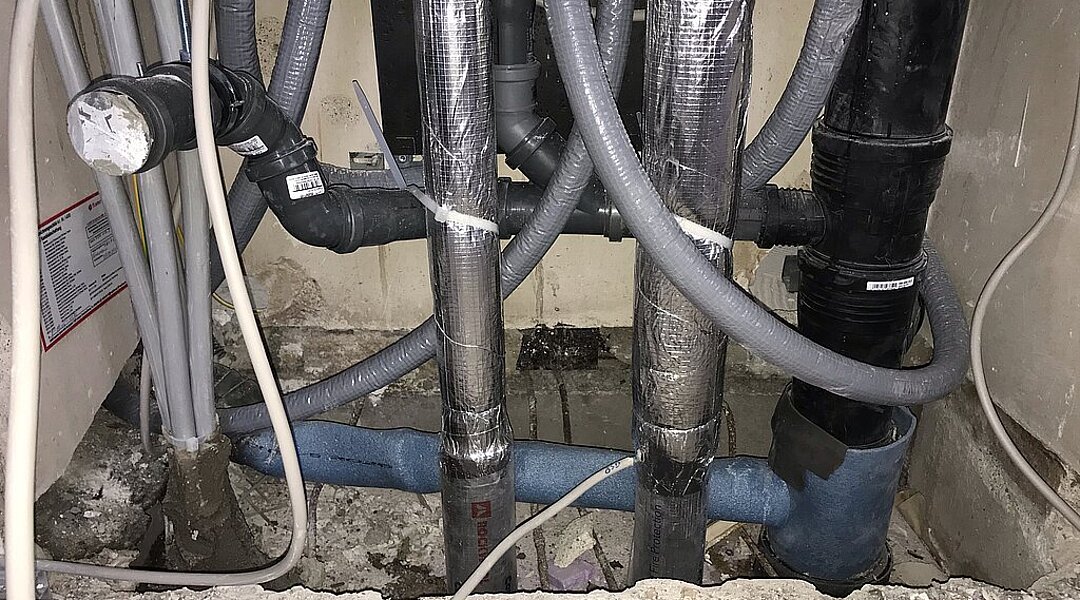 Geöffneter Installationsschacht mit neuen Trinkwasser- und Abwasserleitungen während einer Strangsanierung